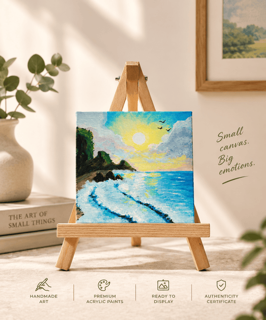 A small square acrylic painting of a beach sunset displayed on a miniature wooden easel. The scene includes decorative props like a vase with green leaves, a book, and framed wall art, with text reading 'Small canvas.