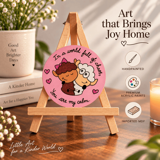 A round acrylic art print featuring a pink background with a cartoon sheep and cat illustration and the text 'In a world full of chaos, You are my calm.' displayed on a small wooden easel.